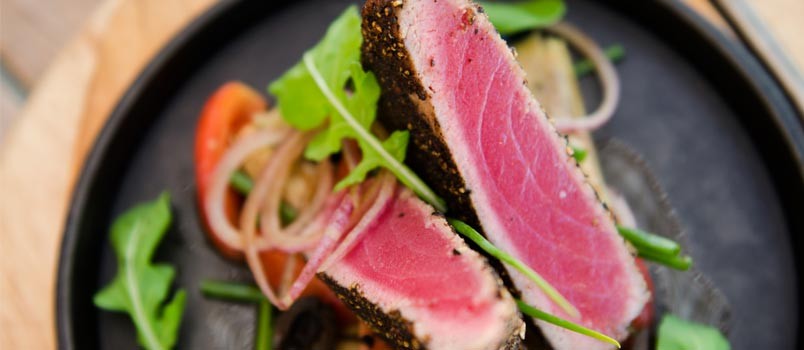 Black Peppered Tuna Steak by Chef Somjit at The Cove Phuket, Ao Yon — grilled tuna with artichokes, olives, and rocket salad.