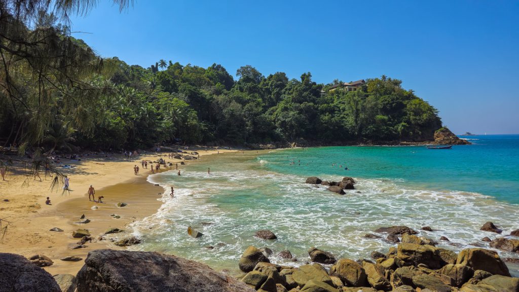 Wide sandy bay with swimmers and forest behind at Banana Beach Phuket.