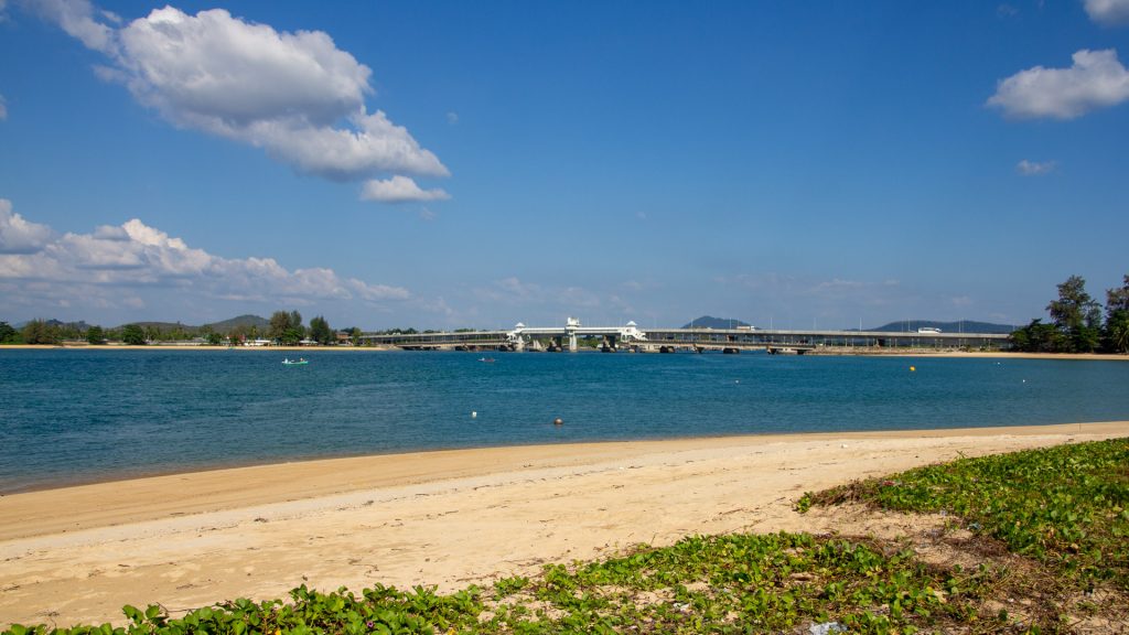Sand shoreline at Haad Pak Phra Beach, Mai Khao, Phuket, facing the Sarasin Bridge across the Pak Phra Strait.
