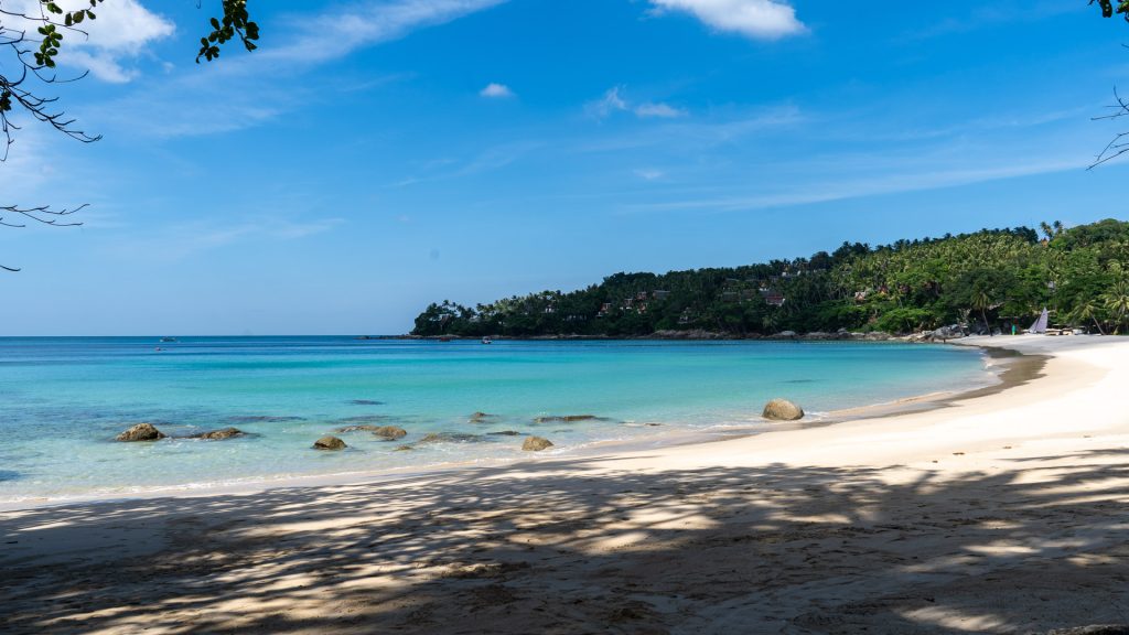 Bright lagoon-like water viewed from shaded beach interior.
