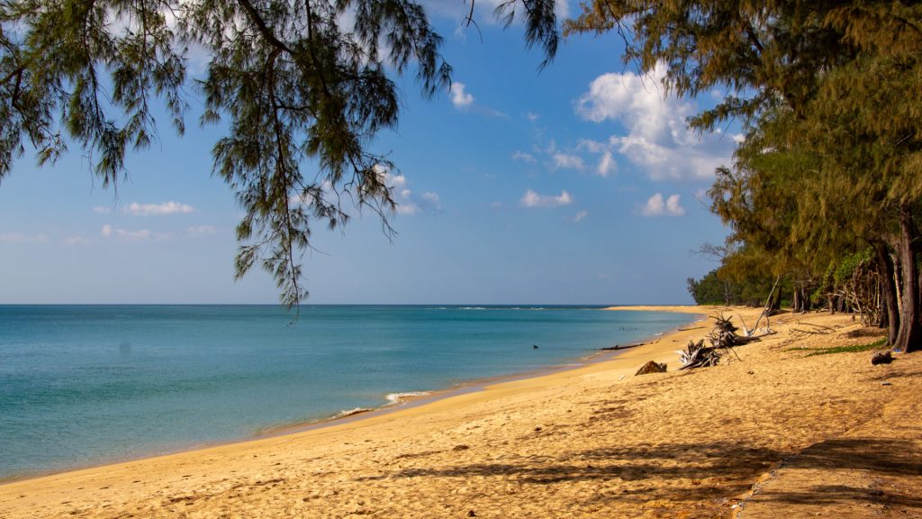 Sai Kaew Beach Phuket with coarse sand, Casuarina branches, and calm water at the Pak Phra Strait.