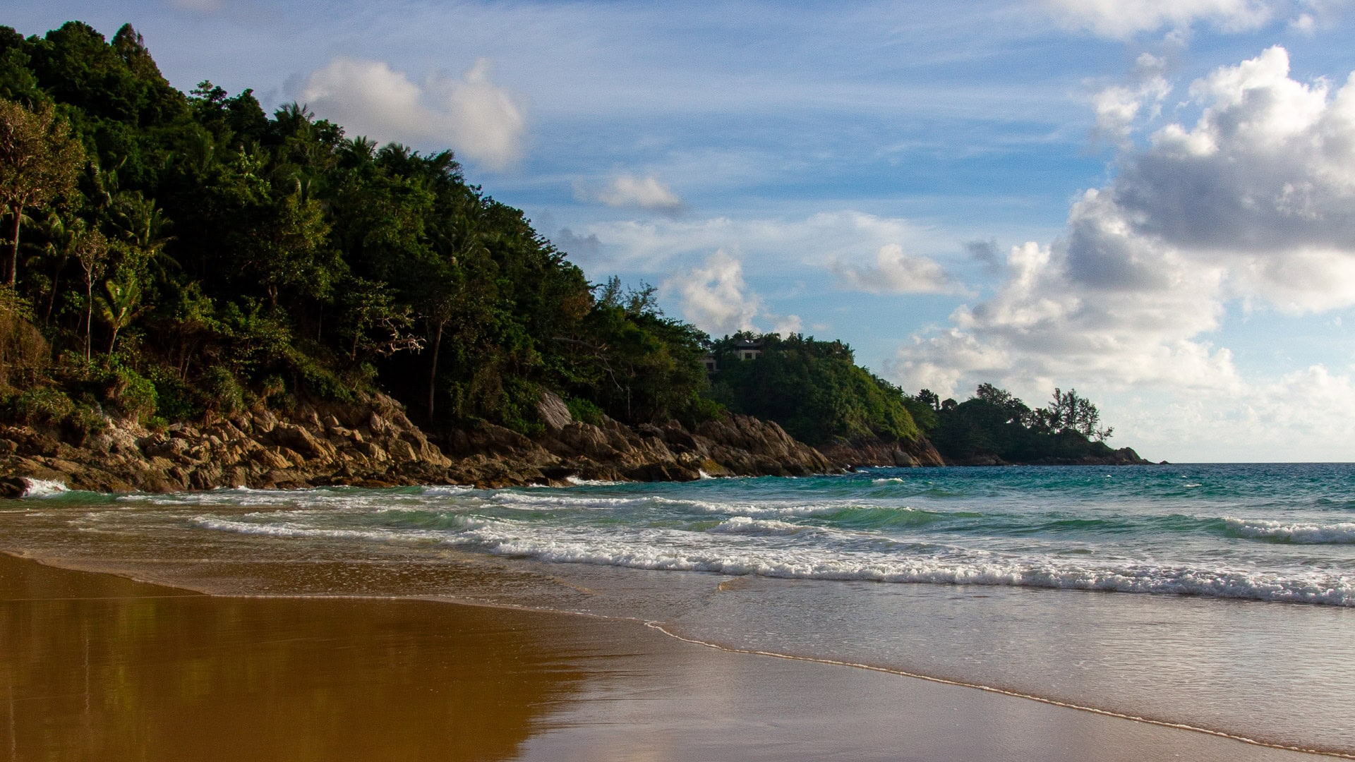 White Beach Phuket small cove with turquoise water and light surf under afternoon sun.