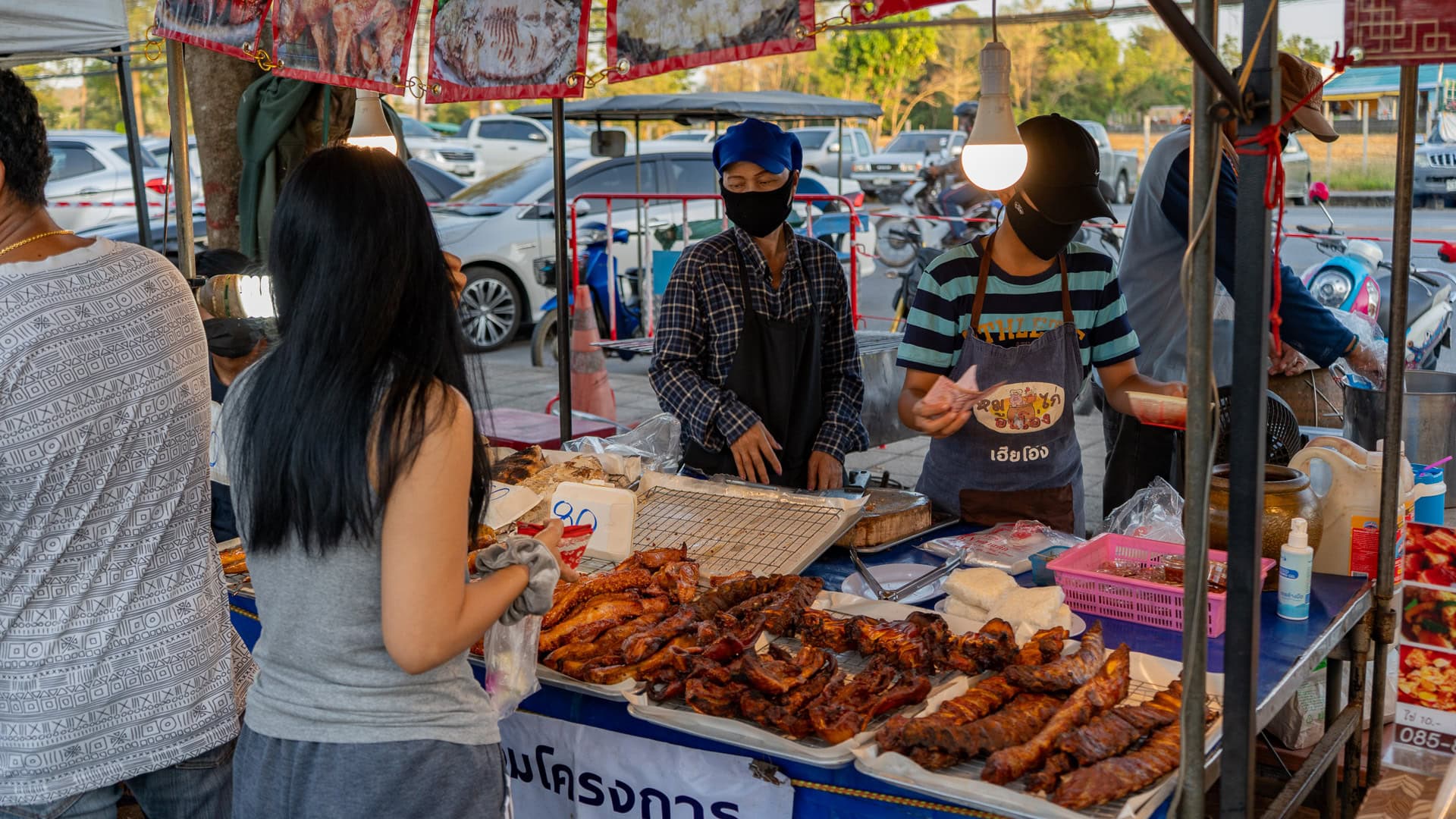 Street food vendor cooking a hot dish on a flat pan at Chaeng Talay Street Food Market beside a busy road.
