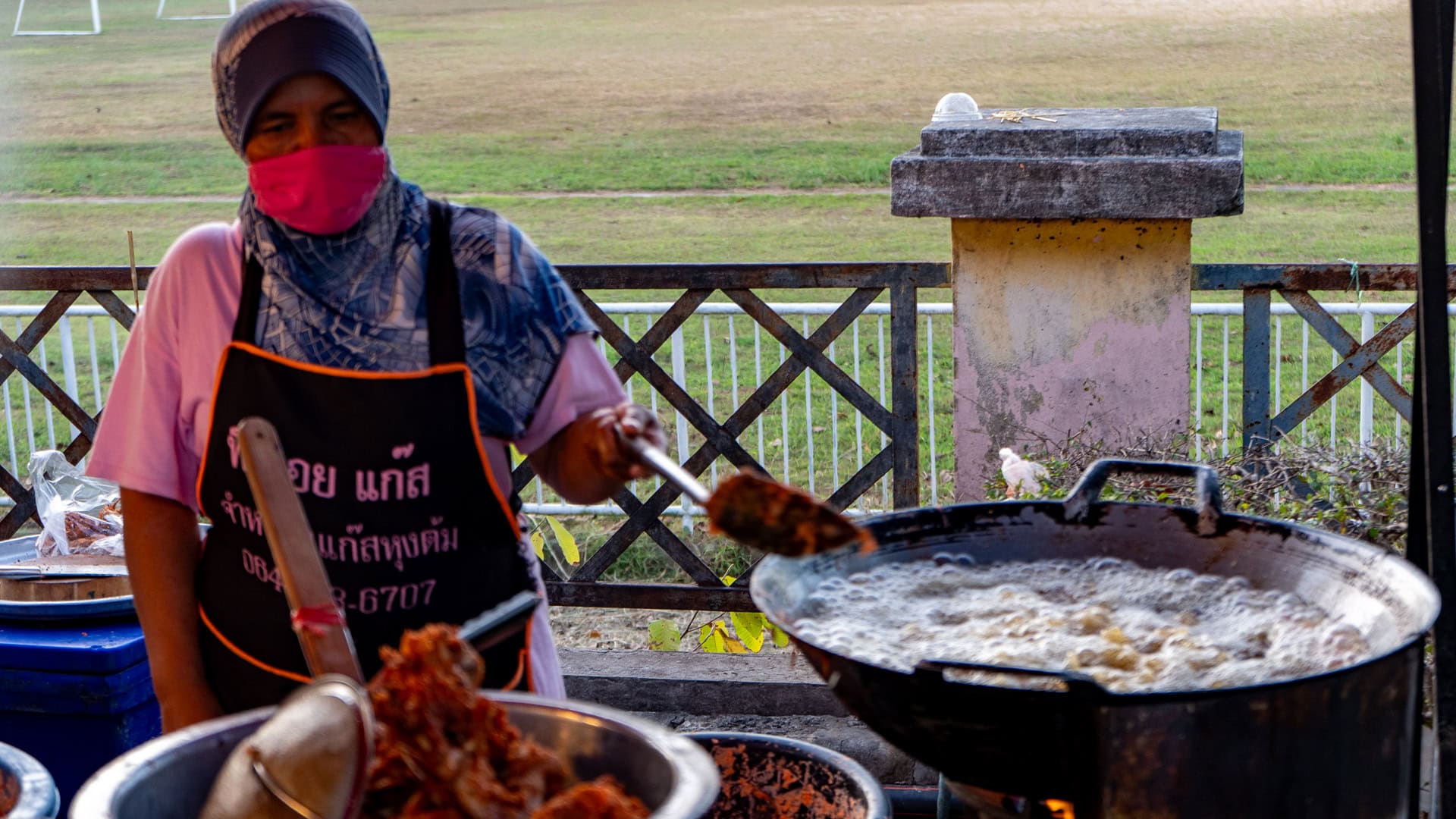 Vendor deep-frying food in a large wok at Chaeng Talay Street Food Market near closing time.
