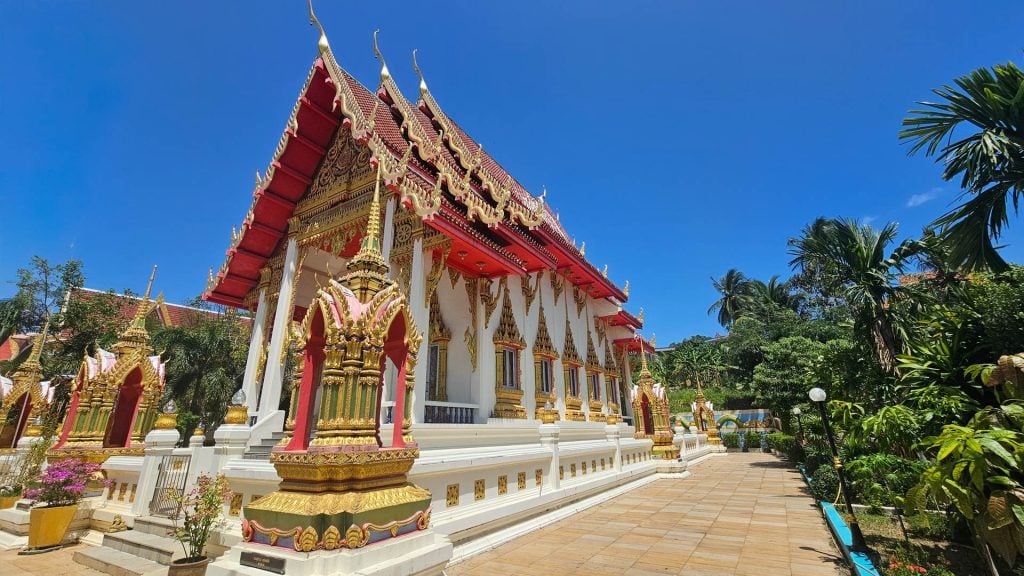 Side view of Wat Karon viharn with walkway and gilded columns