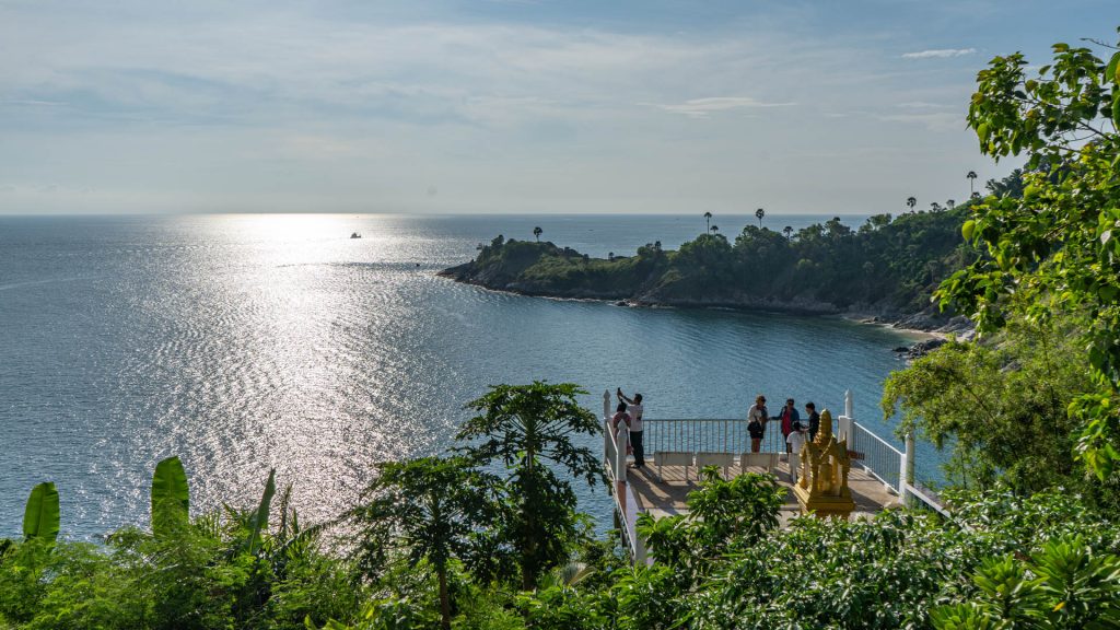 Visitors standing on terrace above the bay at Wat Laem Phromthep