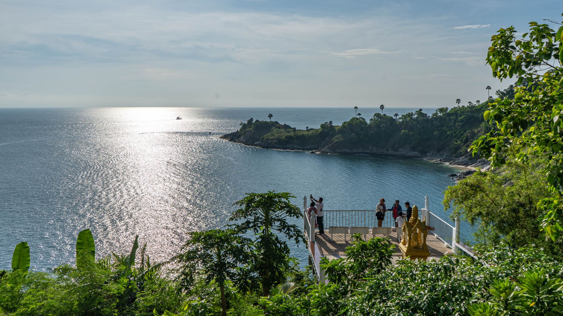 Visitors standing on terrace above the bay at Wat Laem Phromthep