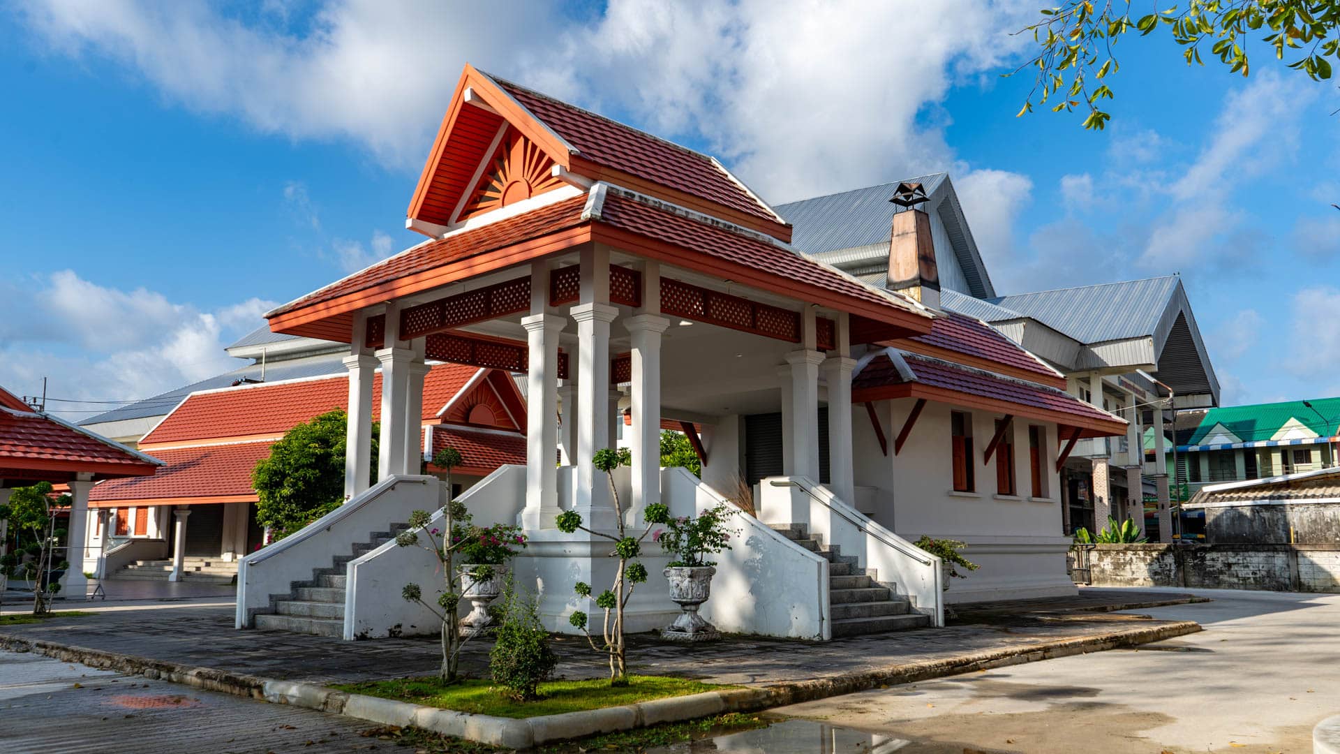 Raised pavilion with twin staircases and red tiled roof in temple grounds