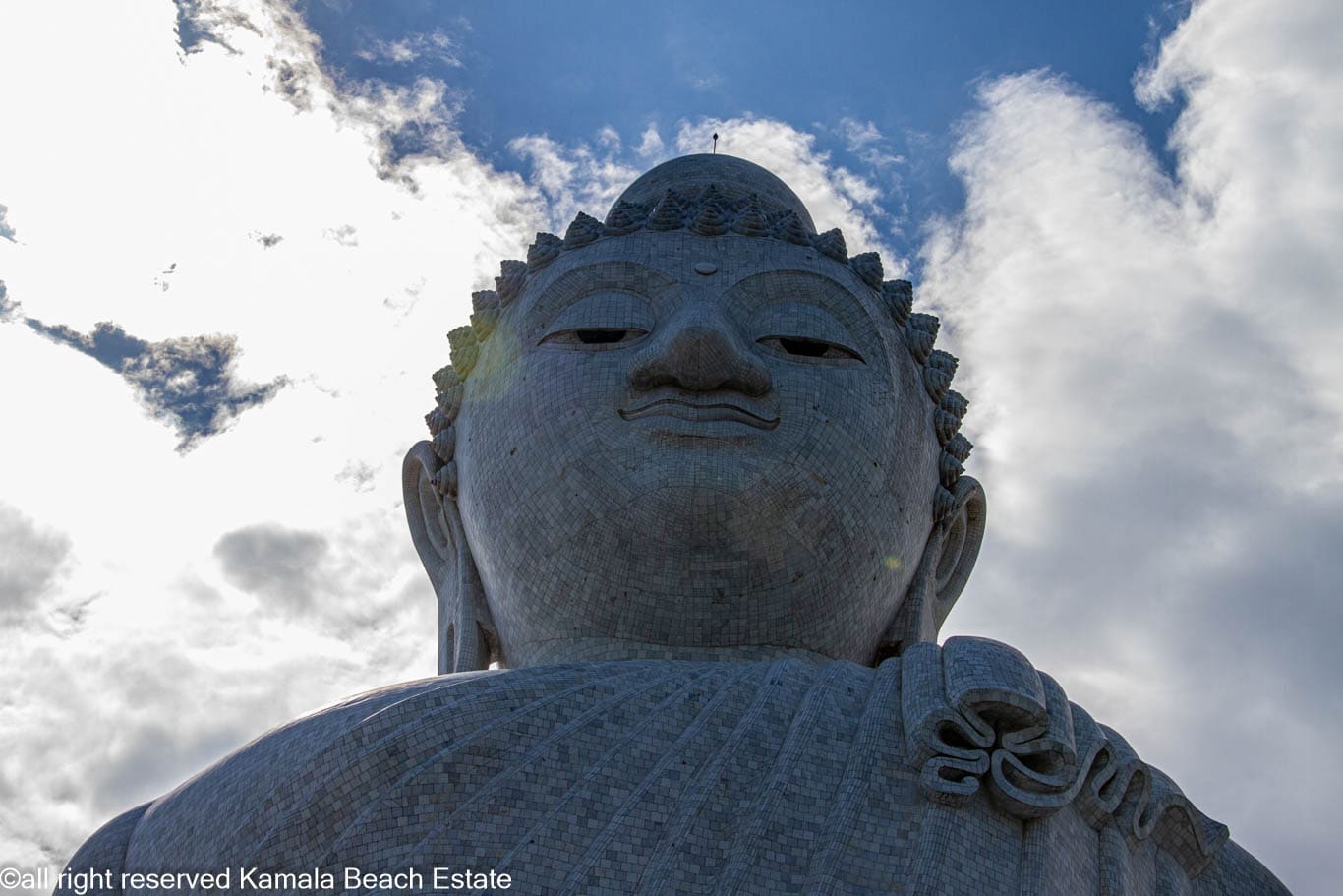 Low-angle close-up of the marble face and robe of Big Buddha Phuket