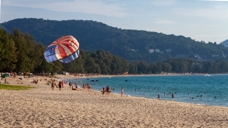 Parasailing off Bang Tao Beach with hills and forest behind.