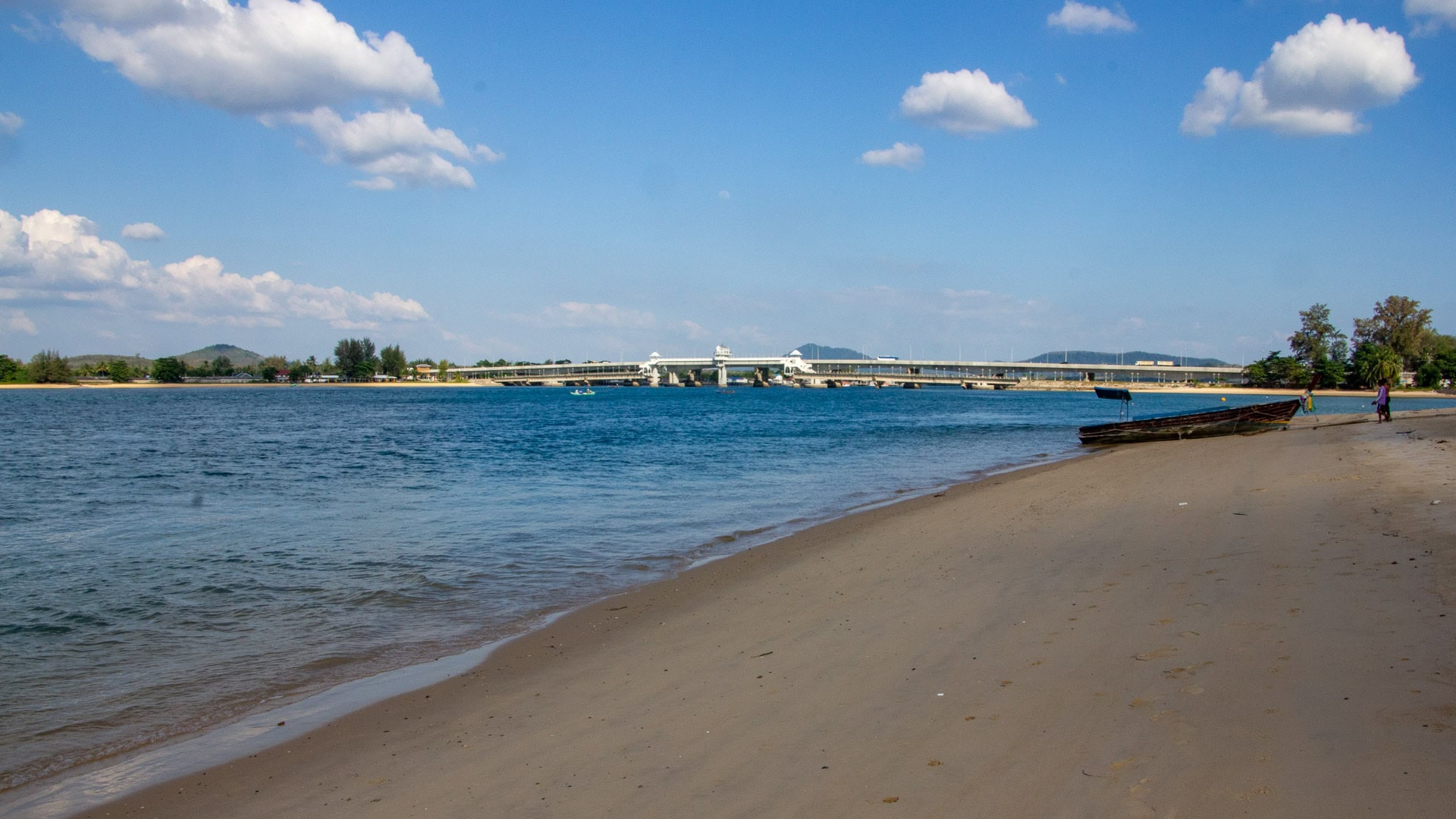 View of the Pak Phra Strait from Haad Pak Phra Beach, Mai Khao, Phuket, with the Sarasin Bridge visible across the channel.