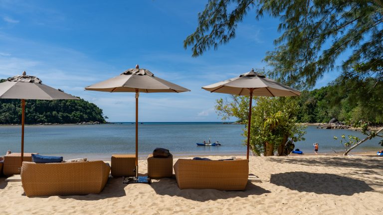 Wicker loungers and umbrellas facing the sea near the headland at Layan Beach.