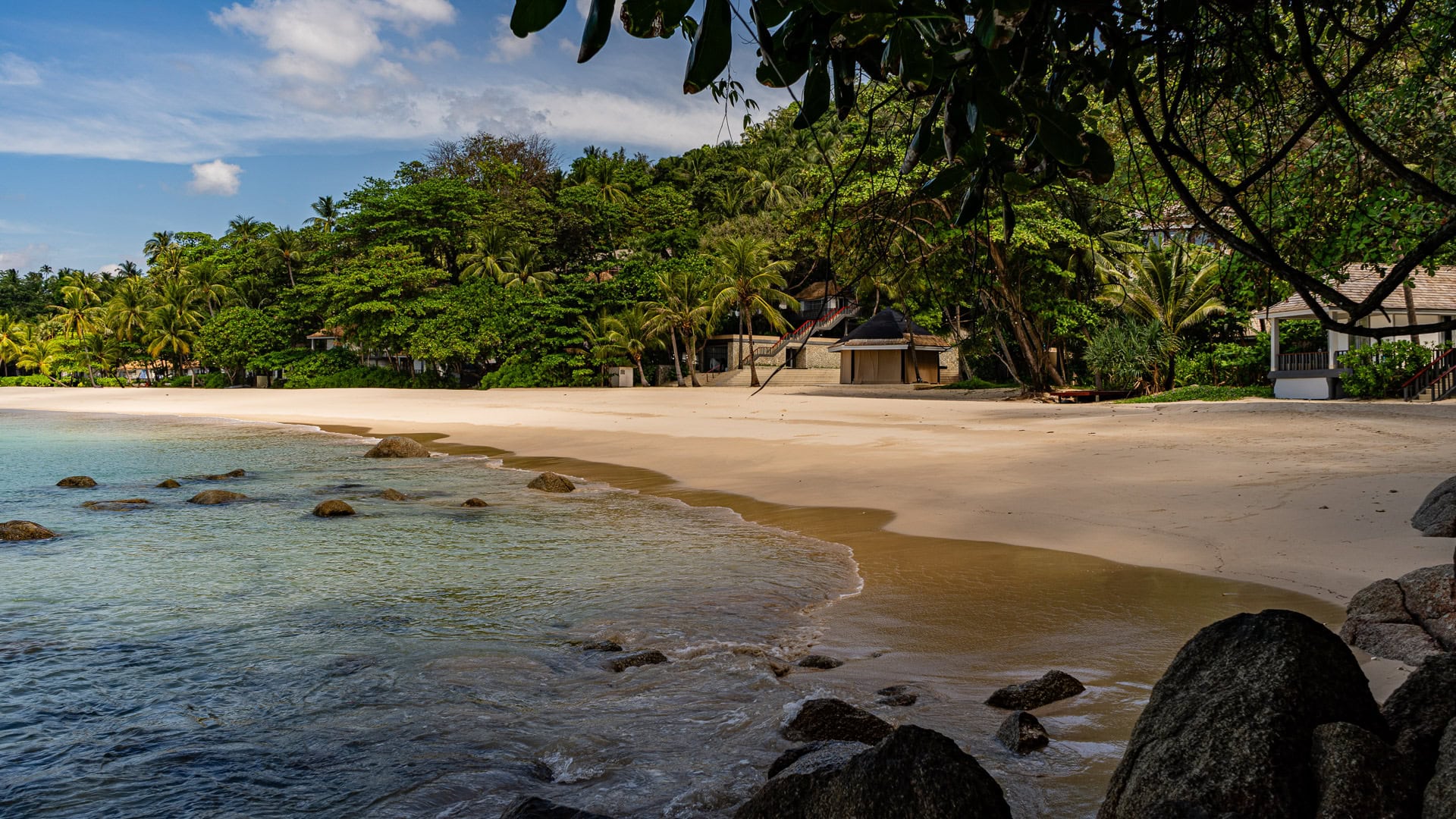 Shallow clear water and white sand curving into a tree-lined cove.