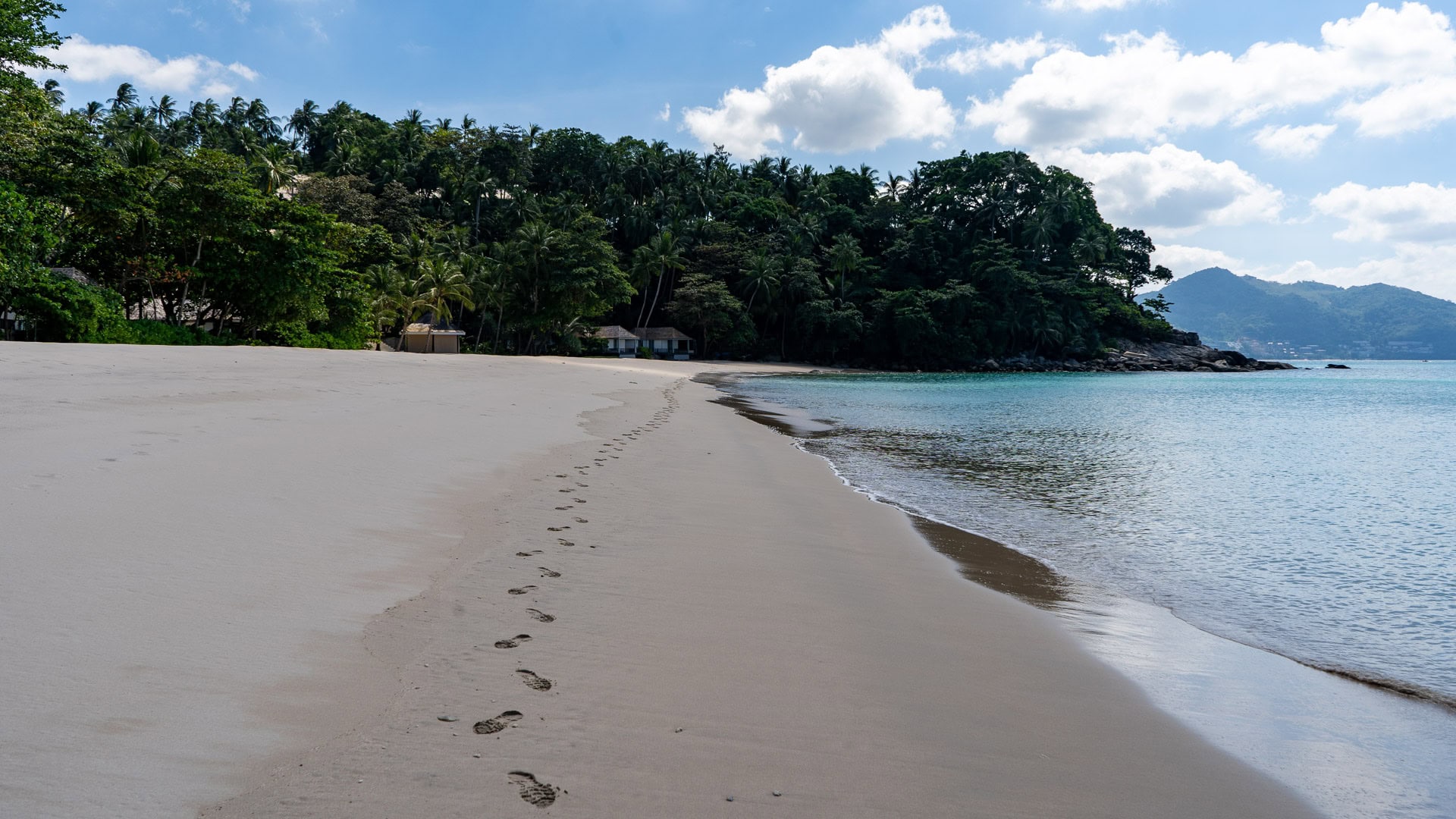 Footprints in fine sand leading along a quiet secluded bay.