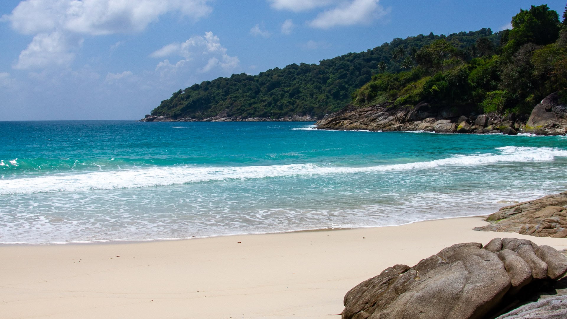Freedom Beach Phuket shoreline with rocks, clear water, and forested headland