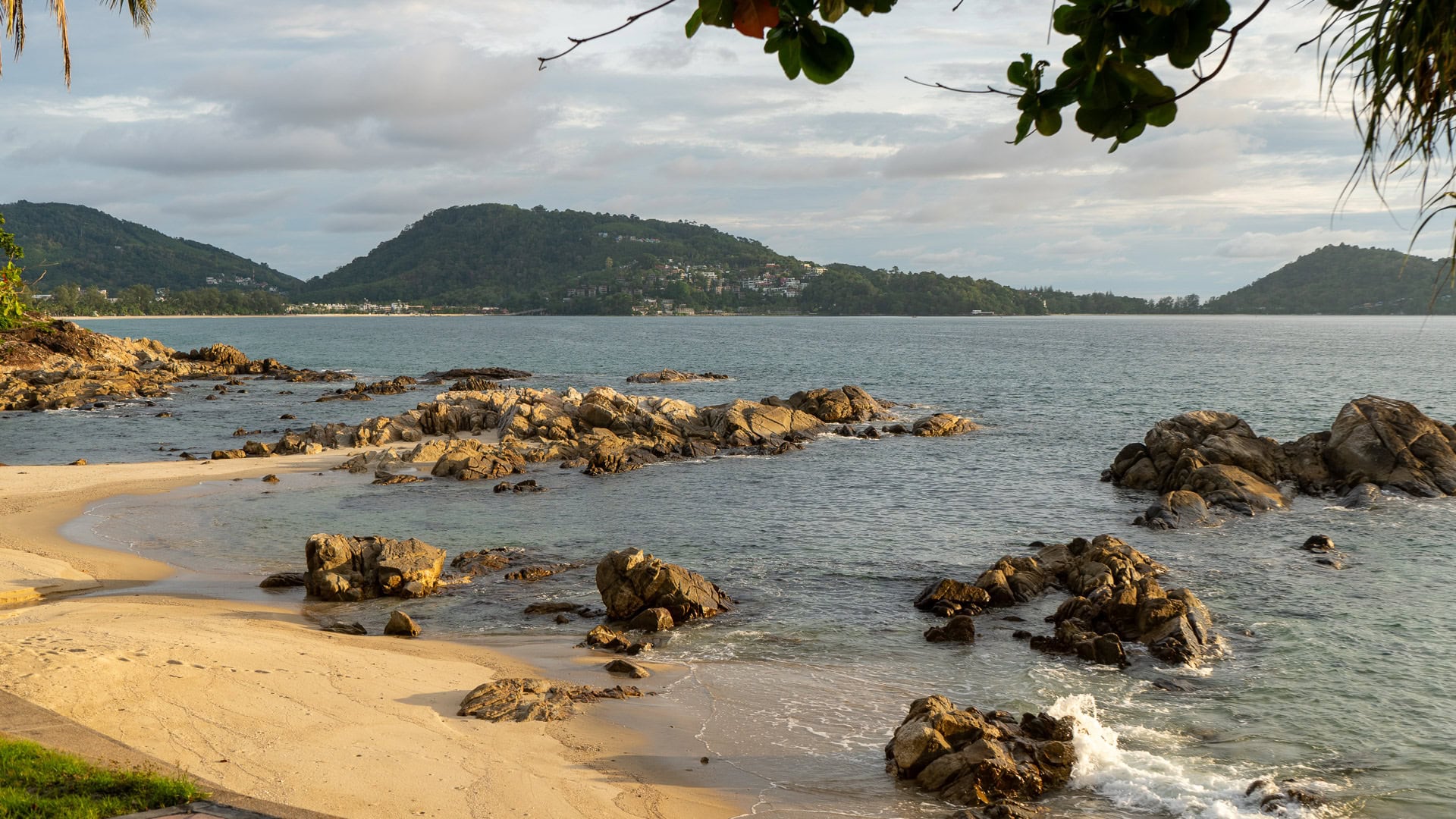Kalim Beach Phuket sandy edge with rocky shoreline and calm waves