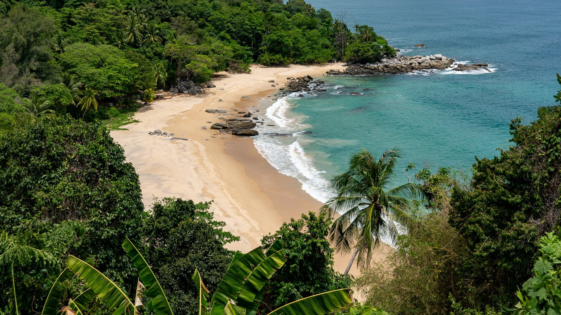 Clear water and submerged rocks along the northern edge of Laem Singh Beach Phuket.