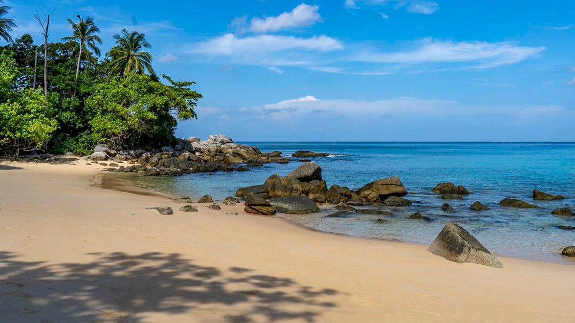 View from the rocks toward the central bay of Laem Singh Beach Phuket with shallow turquoise water.