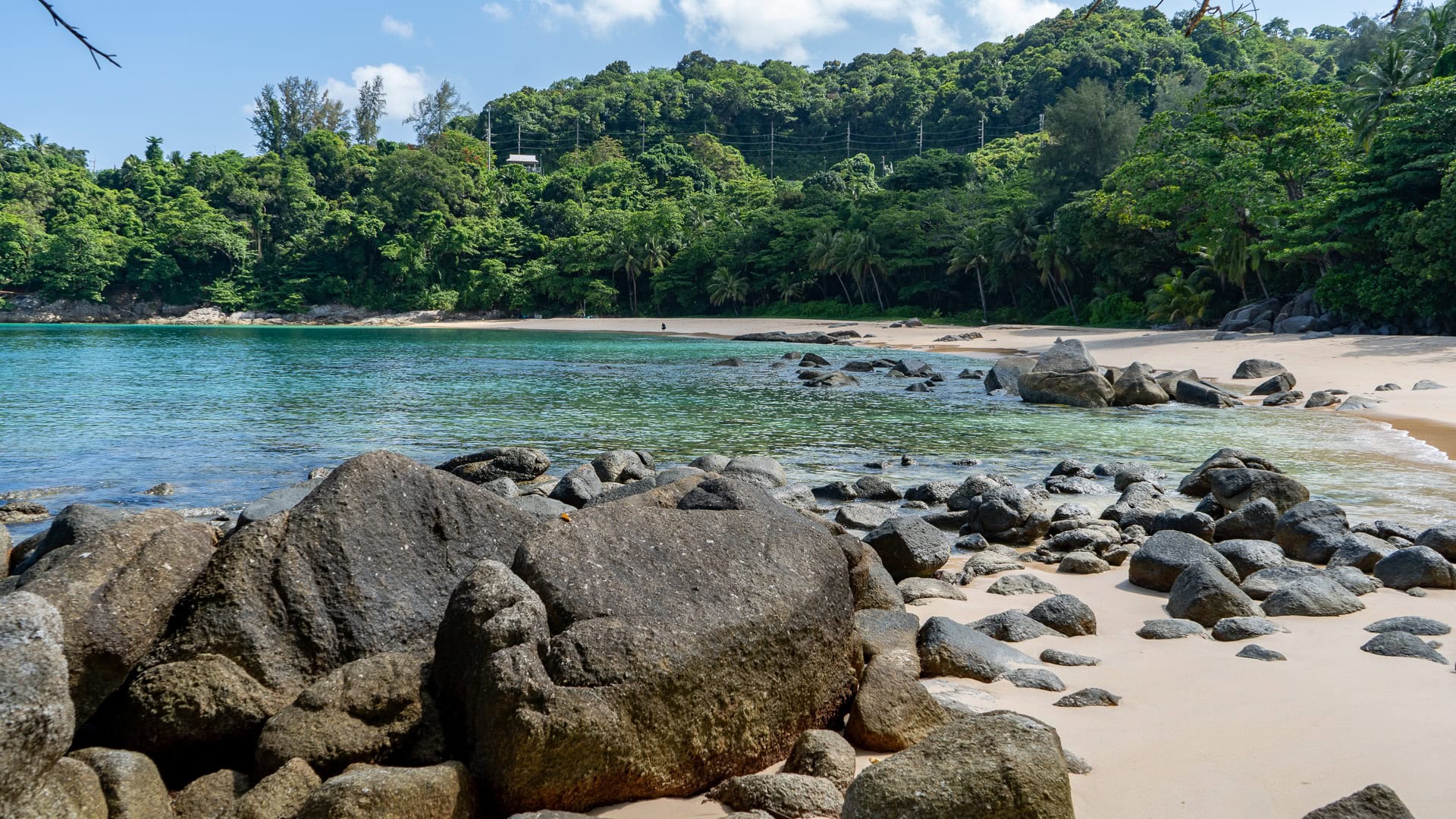 High-angle view showing the full cove shape of Laem Singh Beach Phuket framed by forested hills.