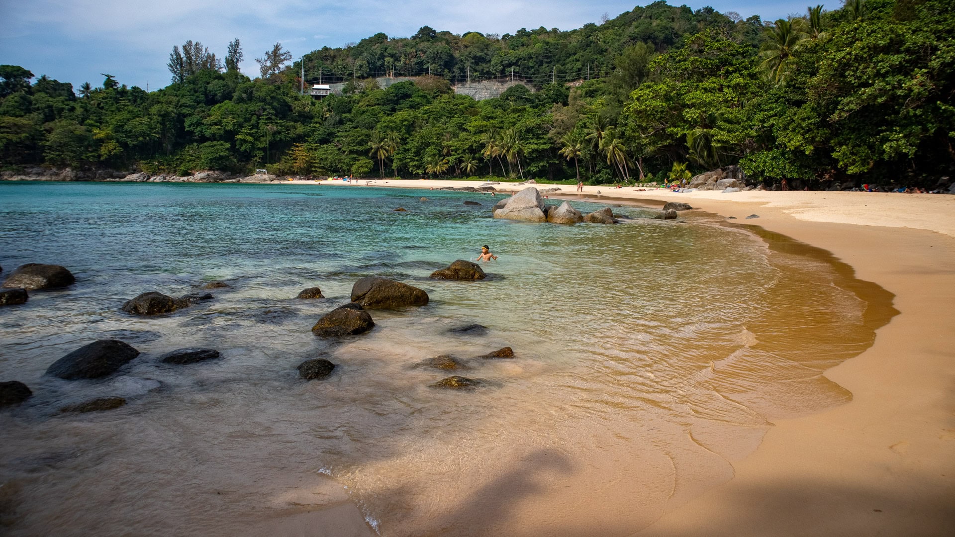 Rock formations and reef zone visible at the shoreline of Laem Singh Beach Phuket.