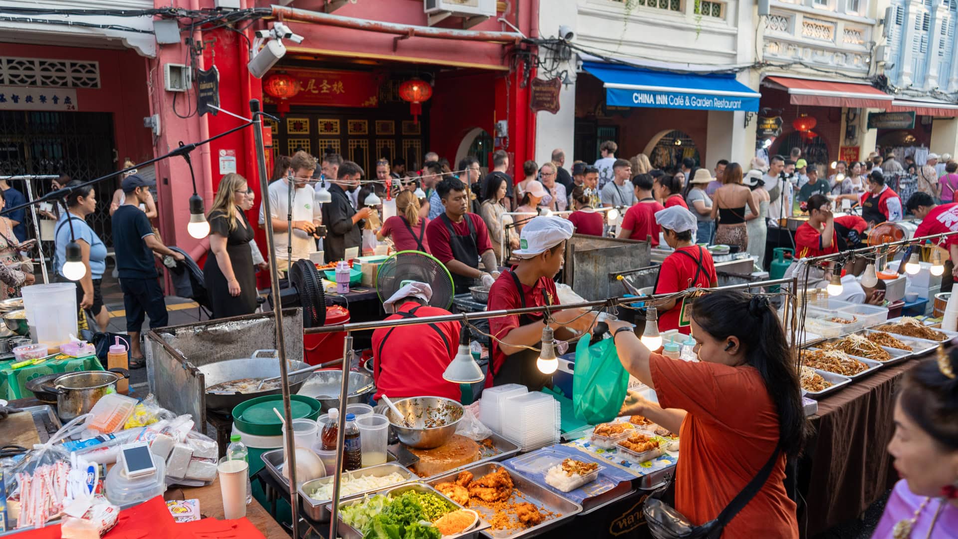 Lard Yai Sunday Night Market Phuket busy food stall with multiple vendors packing takeaway meals from trays of cooked food while customers stand along the counter.