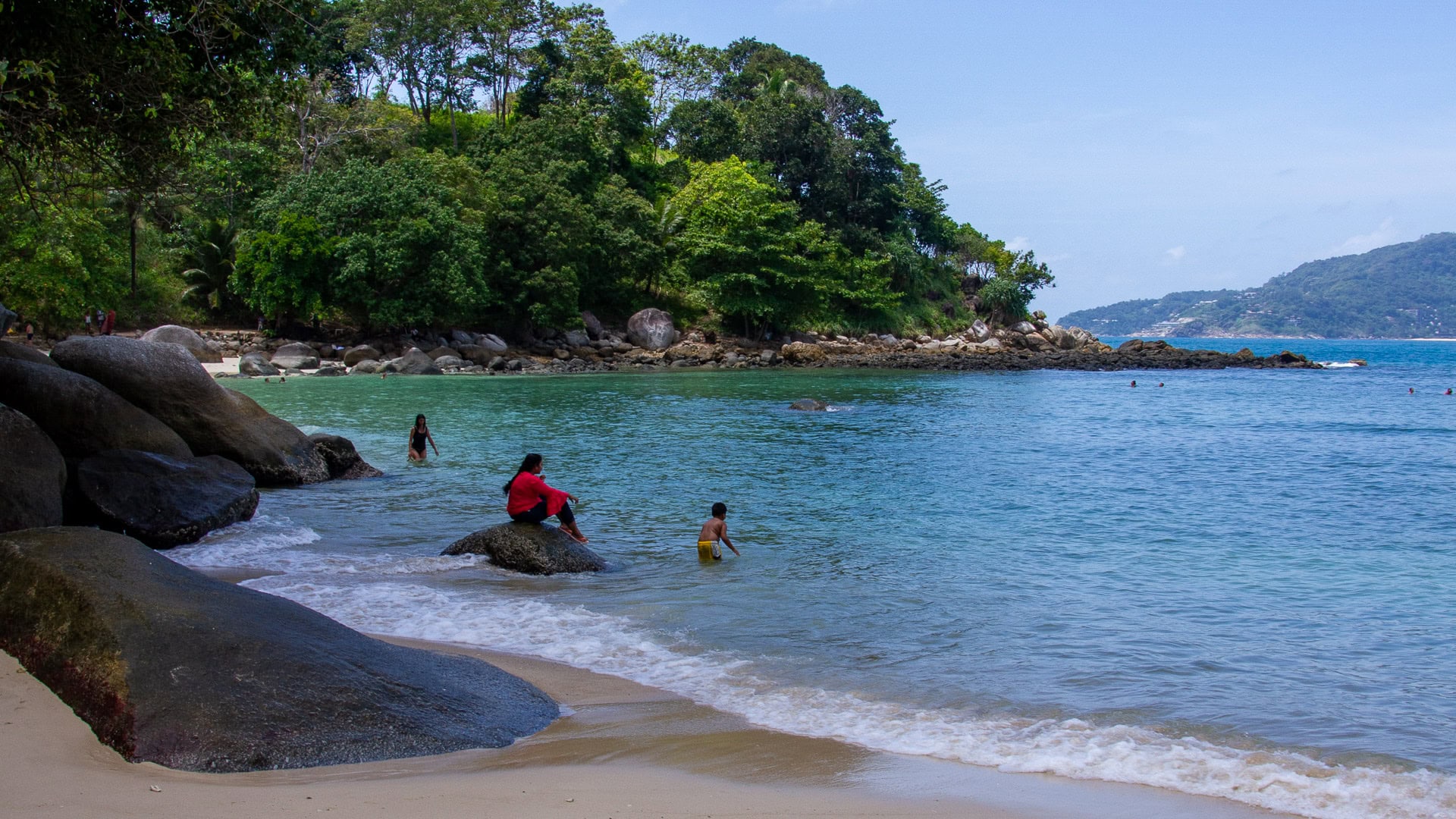 Paradise Beach Phuket rocky edge with people sitting near the water