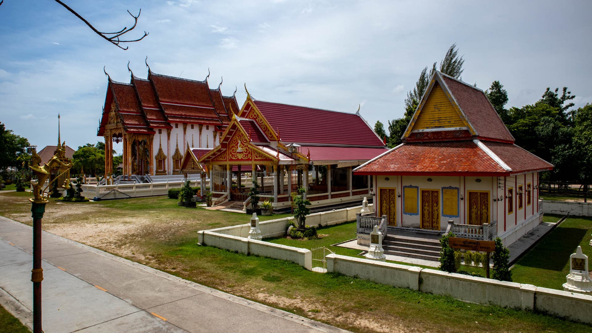 Overview of Wat Chalong temple complex in Phuket showing the main ordination hall and surrounding shrine buildings inside the temple compound.