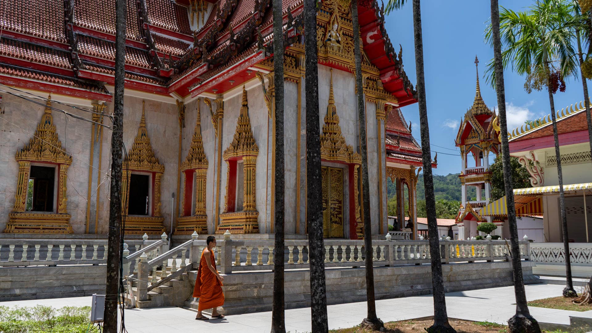 Buddhist monk walking beside temple hall at Wat Chalong Phuket