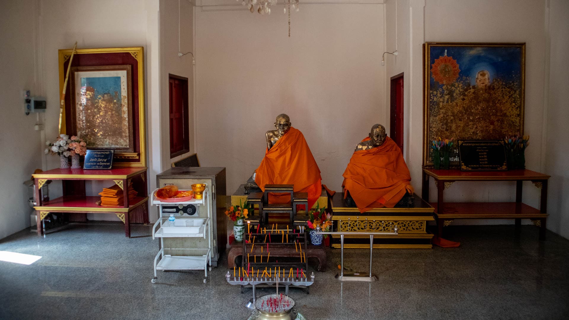 Statues of monks with incense offering altar inside shrine room at Wat Choeng Thale