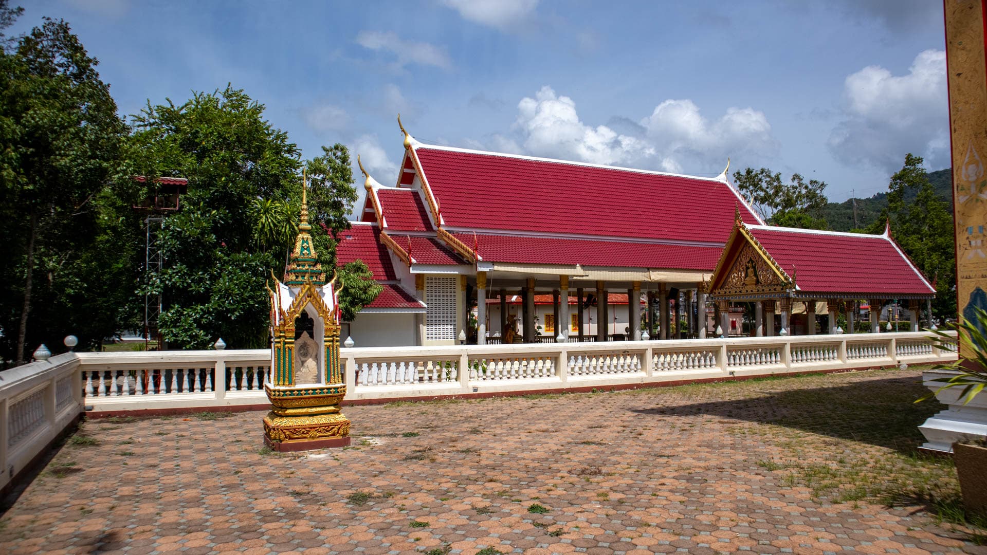 Red roof sermon hall across courtyard at Wat Choeng Thale temple compound
