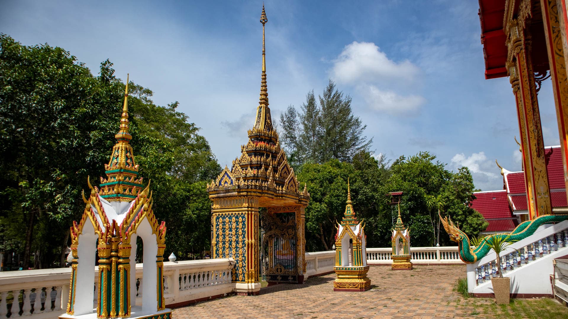Small shrine monuments and chedi structures along courtyard wall at Wat Choeng Thale