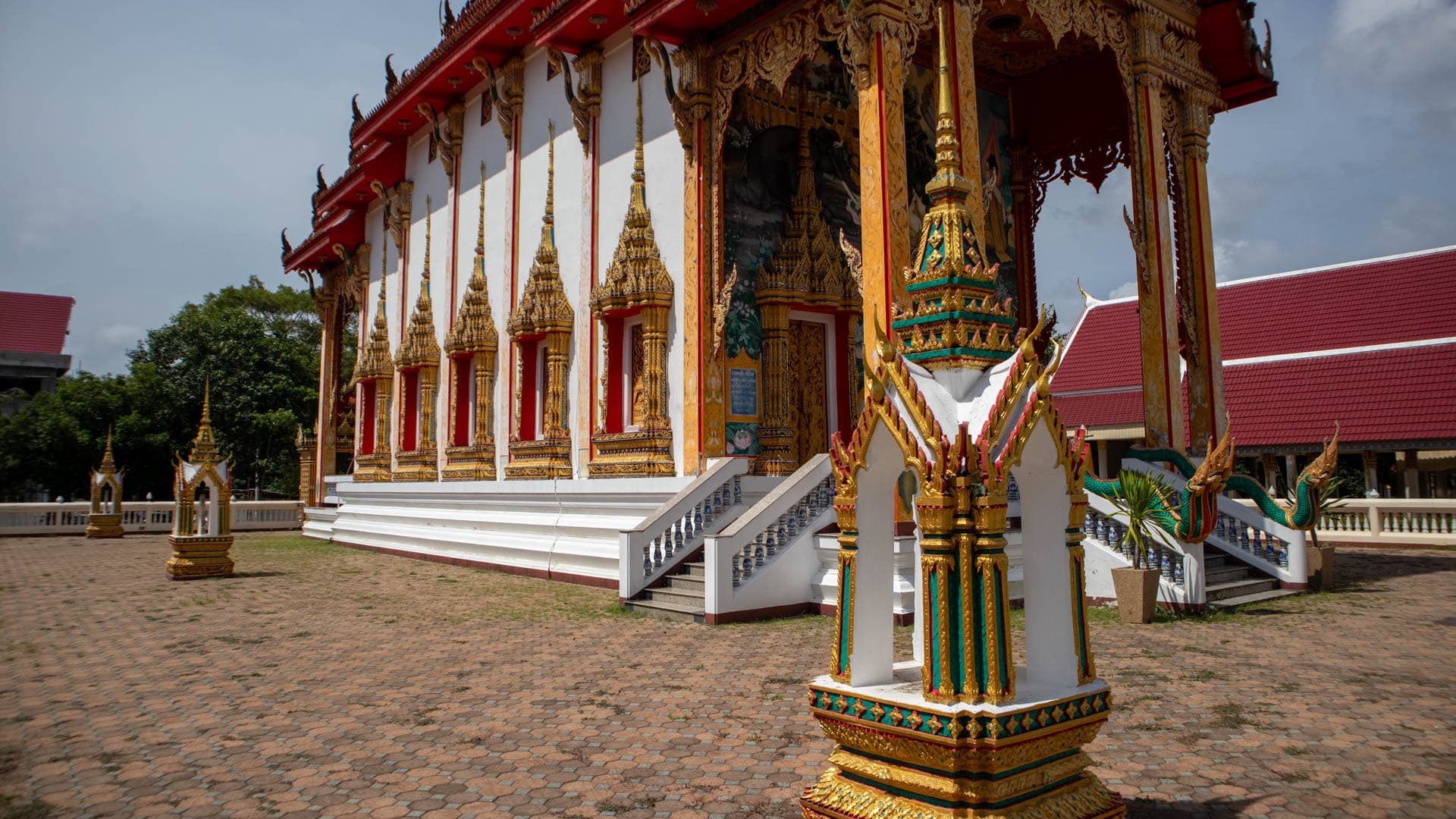 Decorated entrance pavilion with painted ceiling inside Wat Choeng Thale temple compound