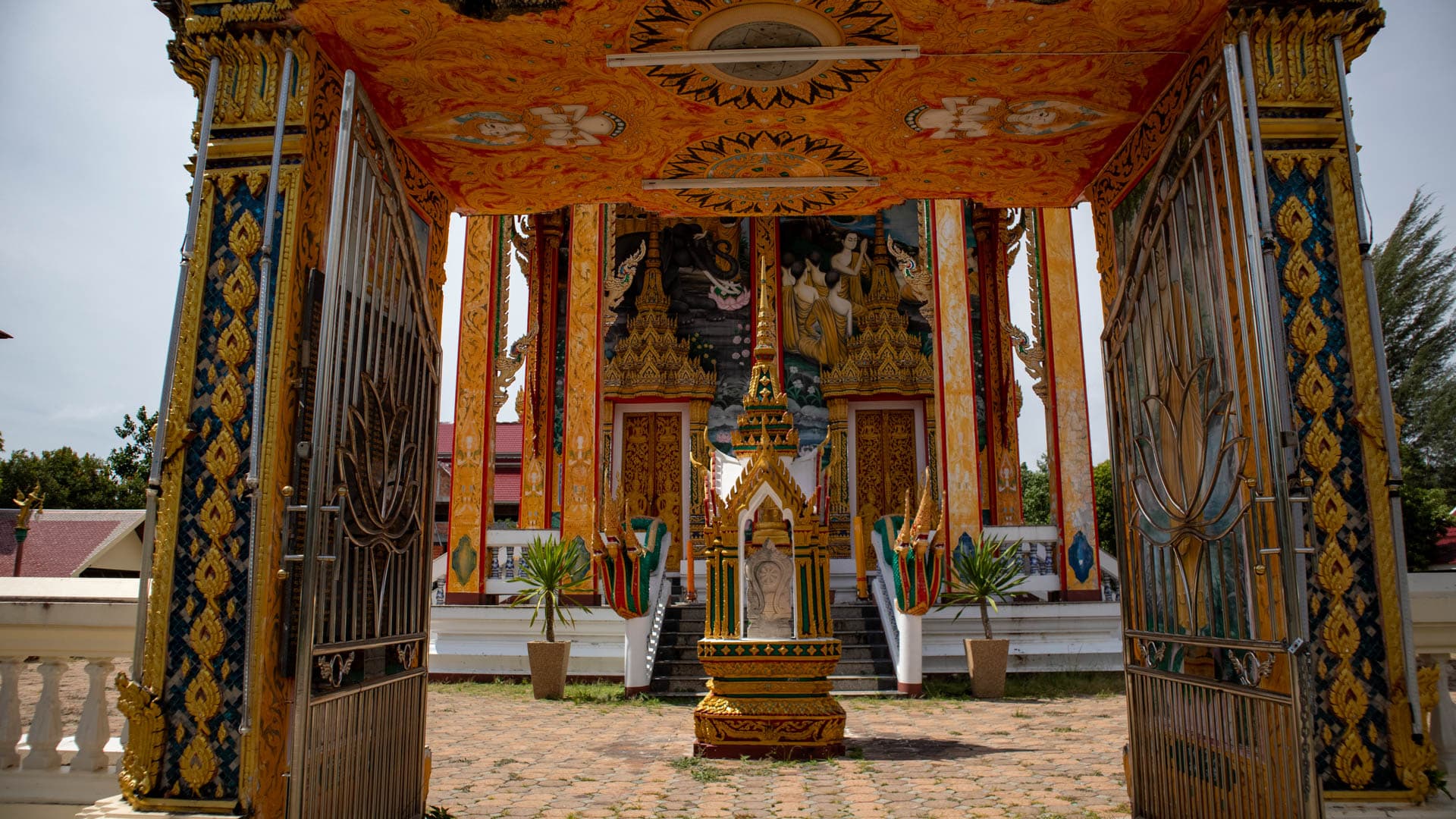 Exterior of Wat Choeng Thale ordination hall with decorated columns and mural panels