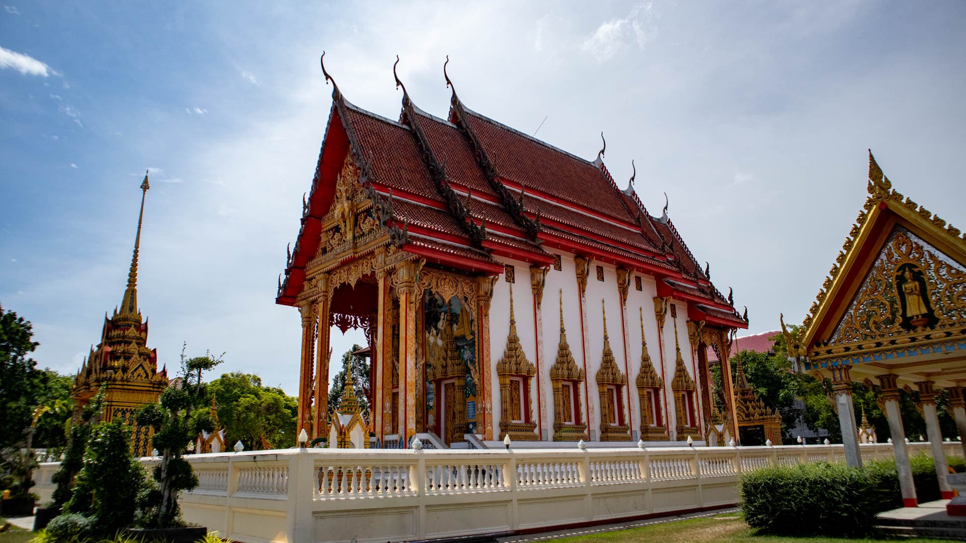 Wat Choeng Thale ordination hall behind courtyard wall with red tiled roof