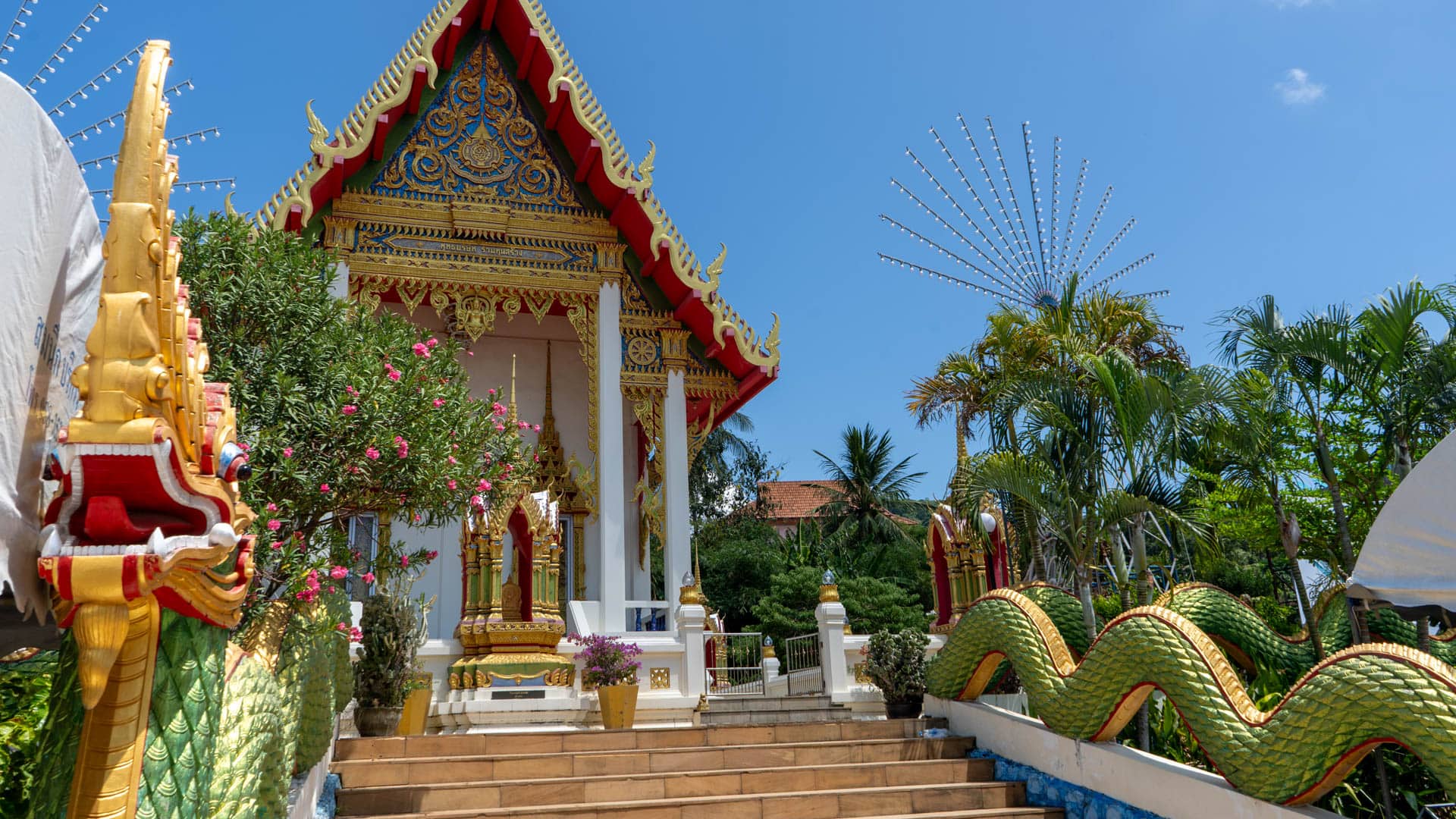 Front view of Wat Karon viharn with naga stairway in temple courtyard