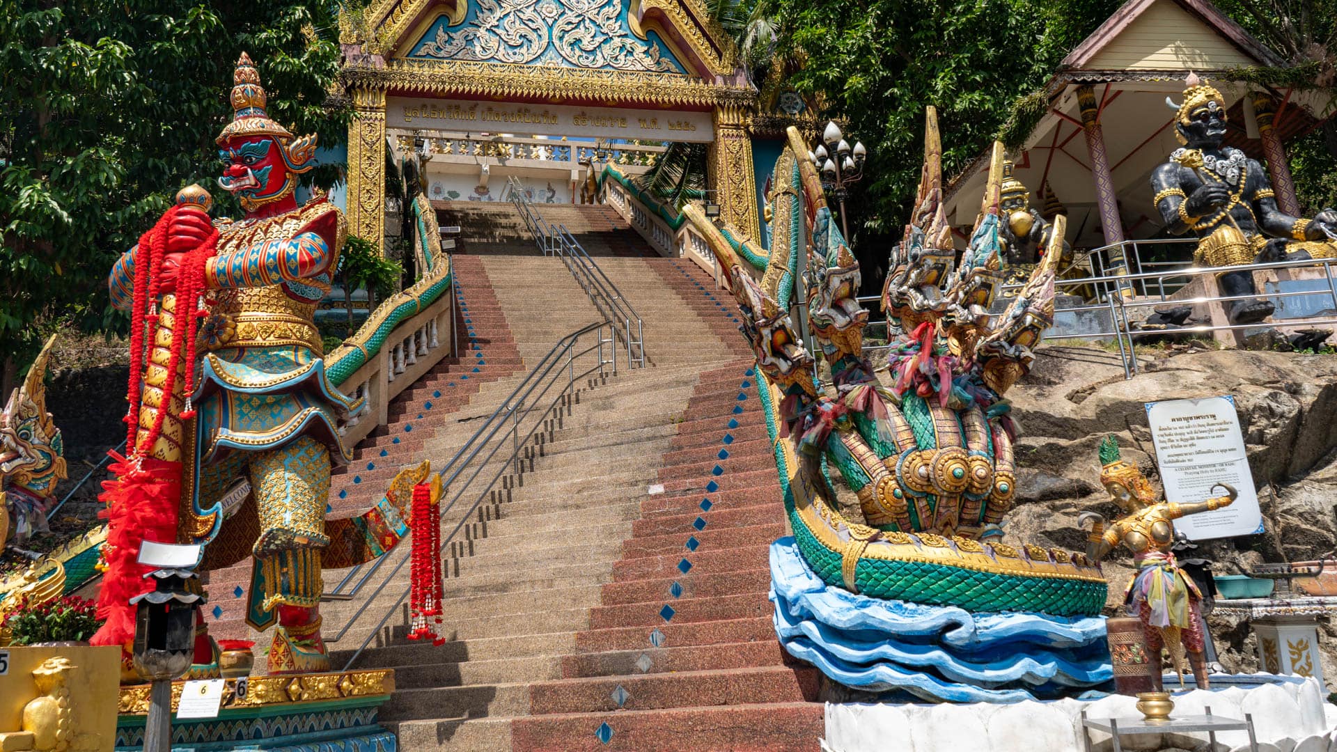 Temple stairway with guardian statue and naga railings at Wat Khao Rang Samakkhitham
