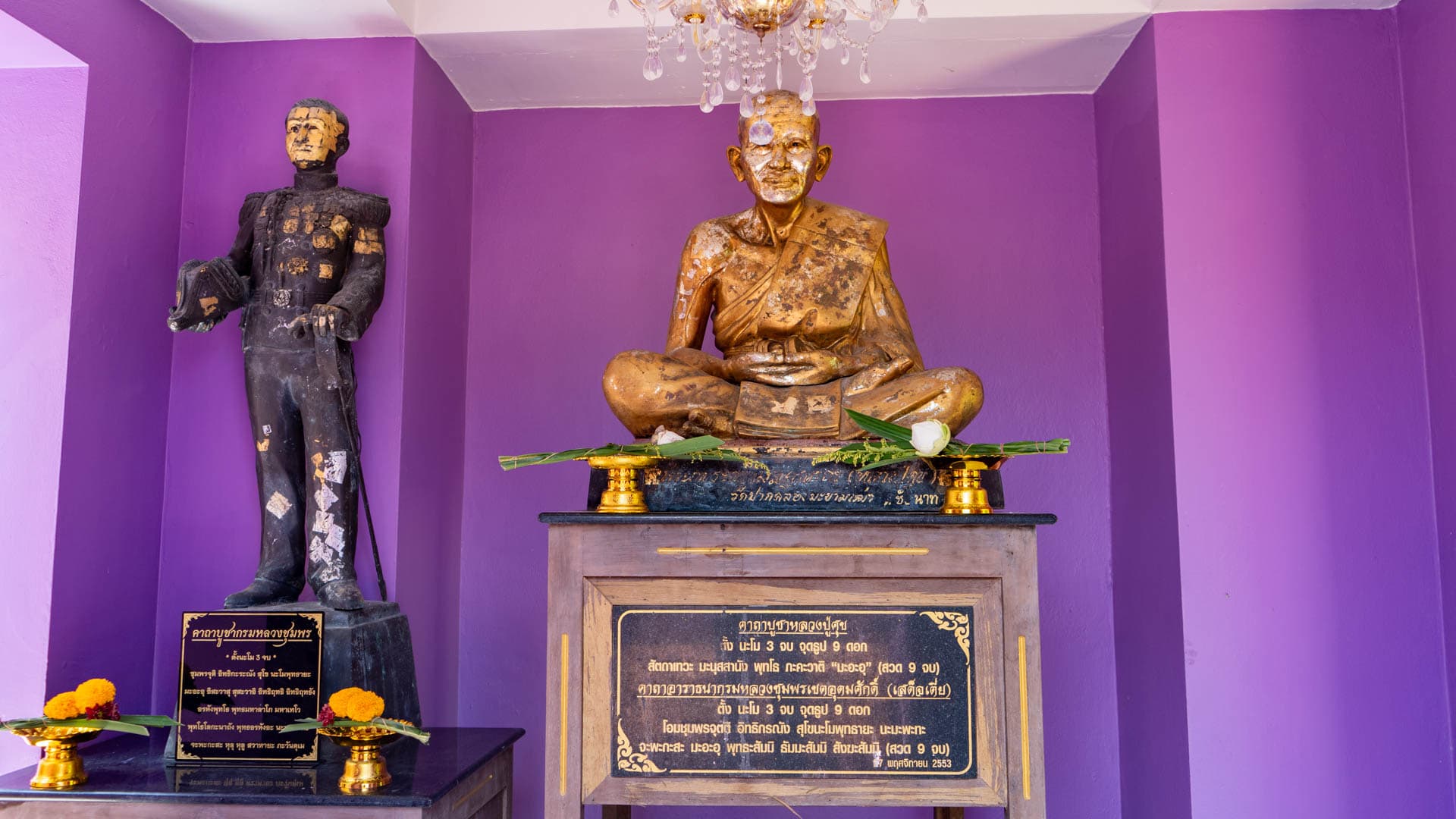Monk statue and memorial figure displayed in shrine room with offerings
