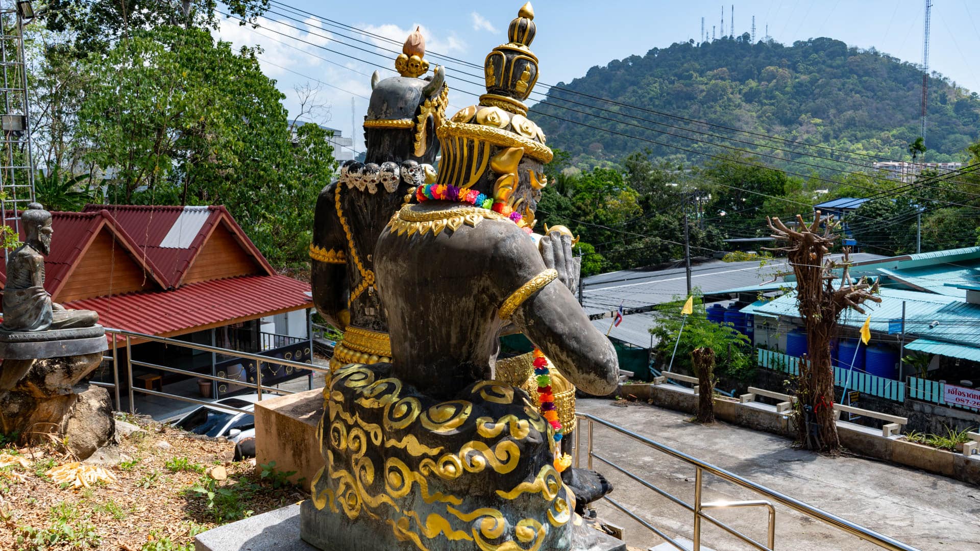 Temple guardian statues on terrace overlooking rooftops and hillside in Phuket Town