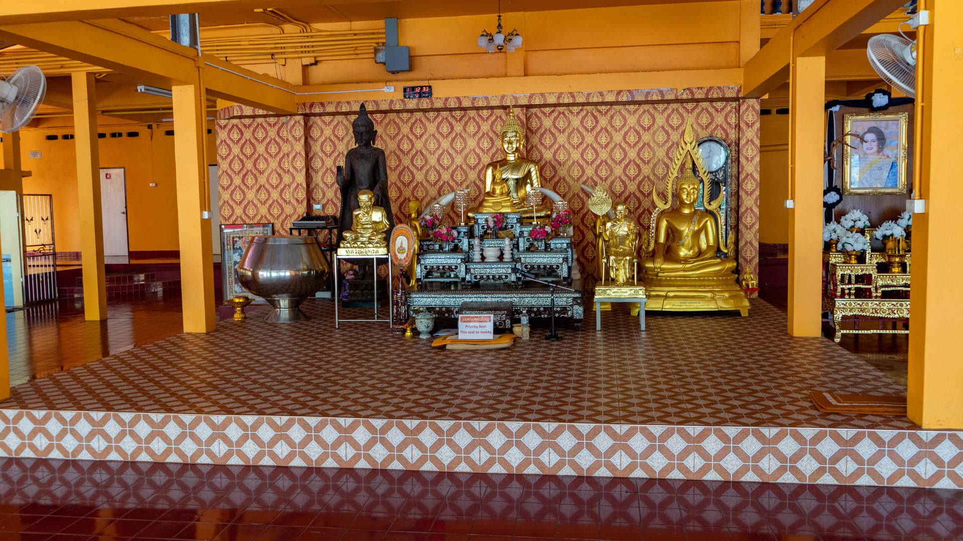 Multiple Buddha statues on altar inside temple hall with patterned wall