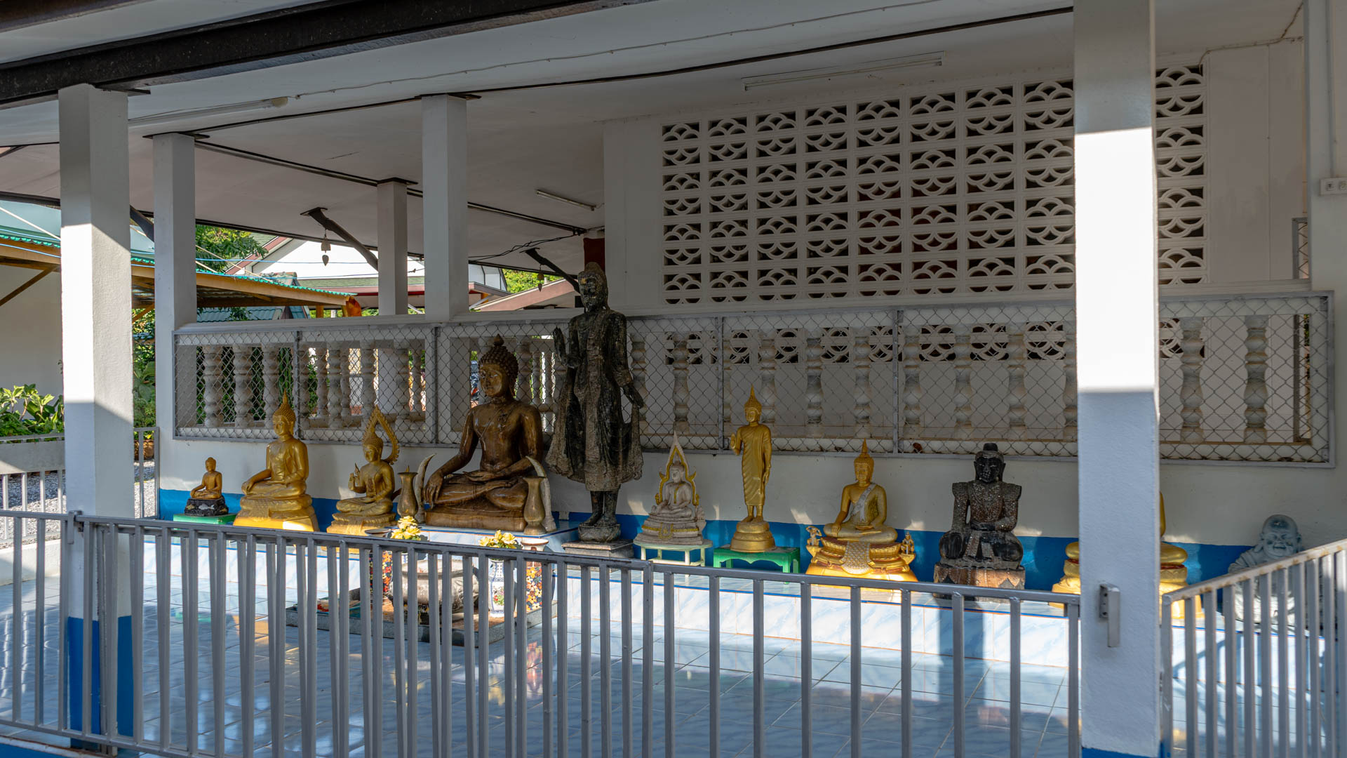 Row of Buddha statues beneath covered pavilion at Wat Laem Phromthep monastery