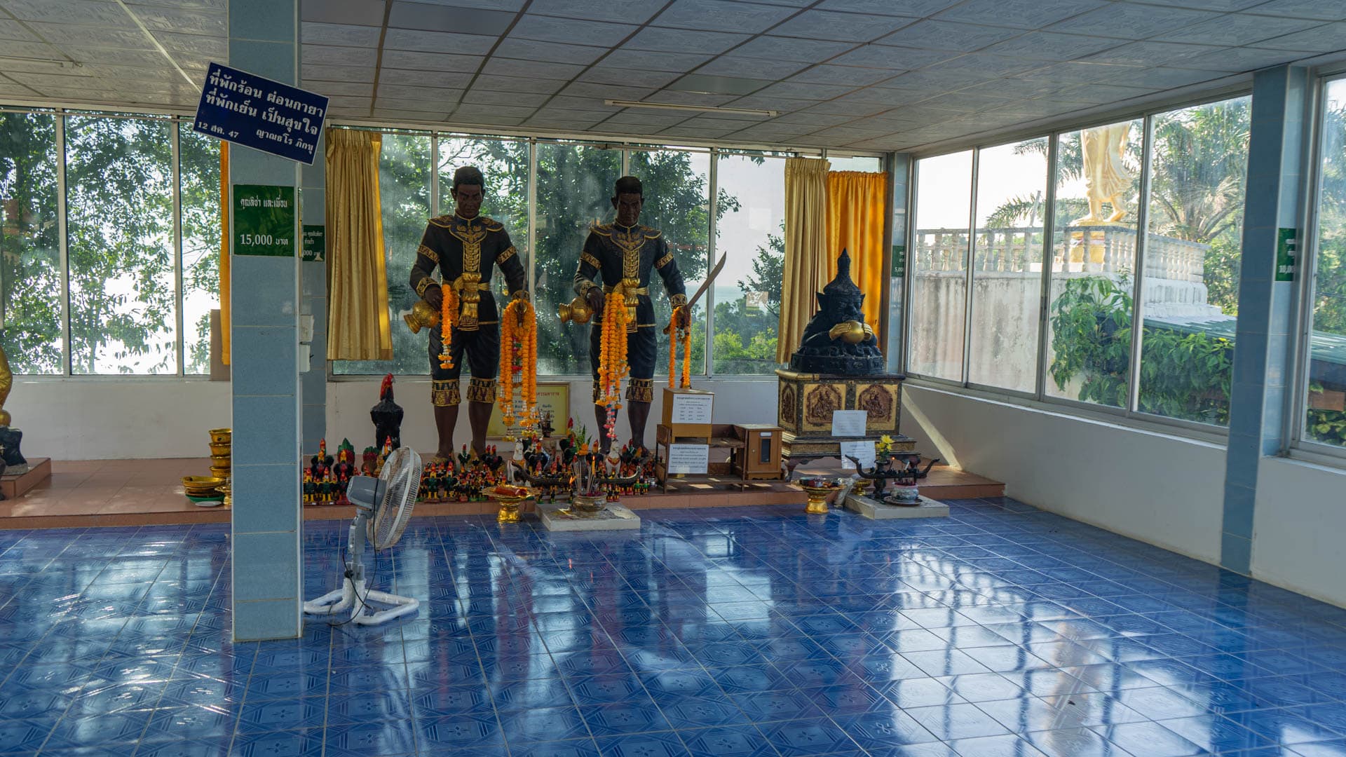 Guardian figures with garlands in shrine room with blue tiled floor