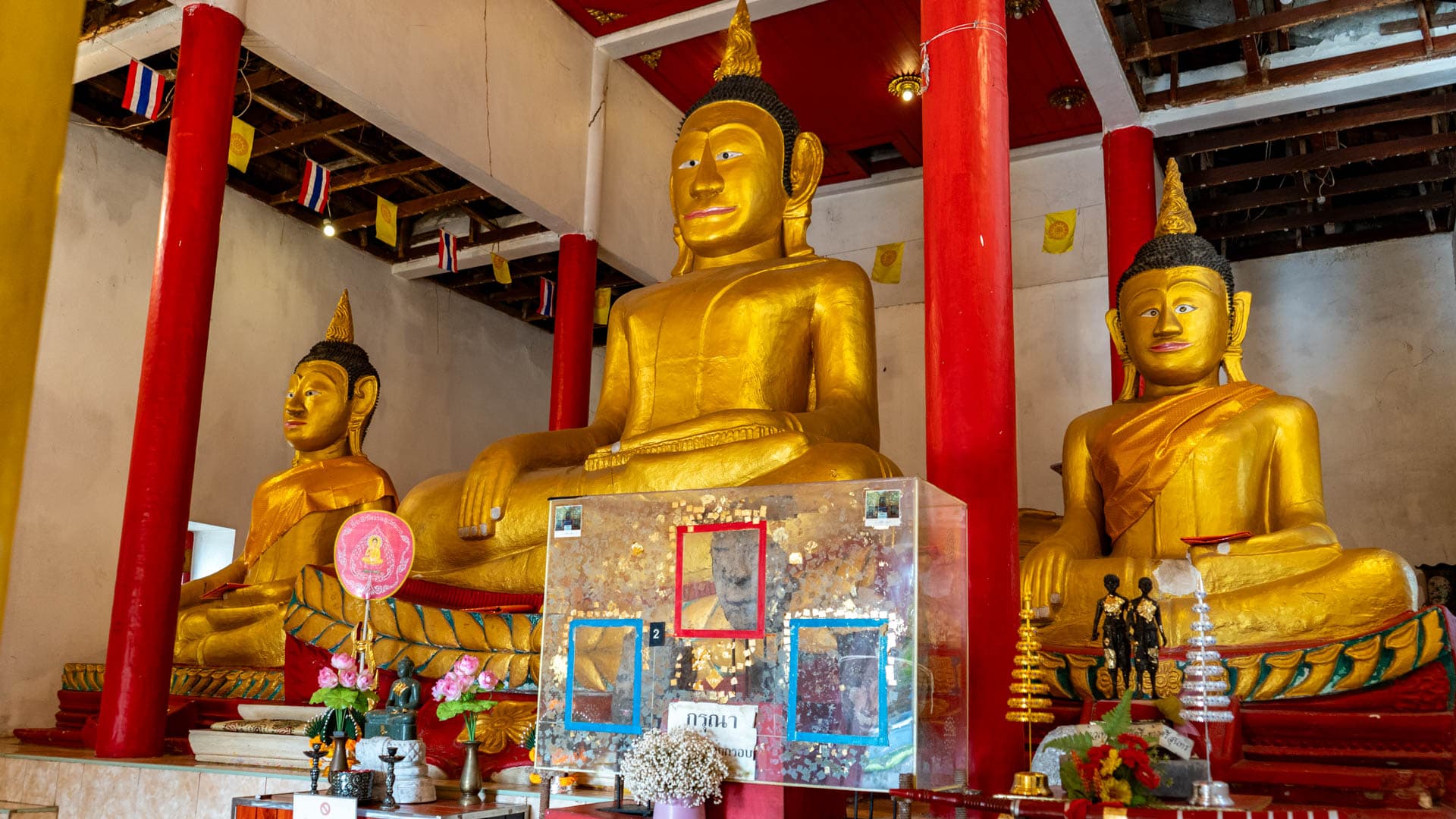 Three large Buddha images and enclosed tin heads inside temple hall