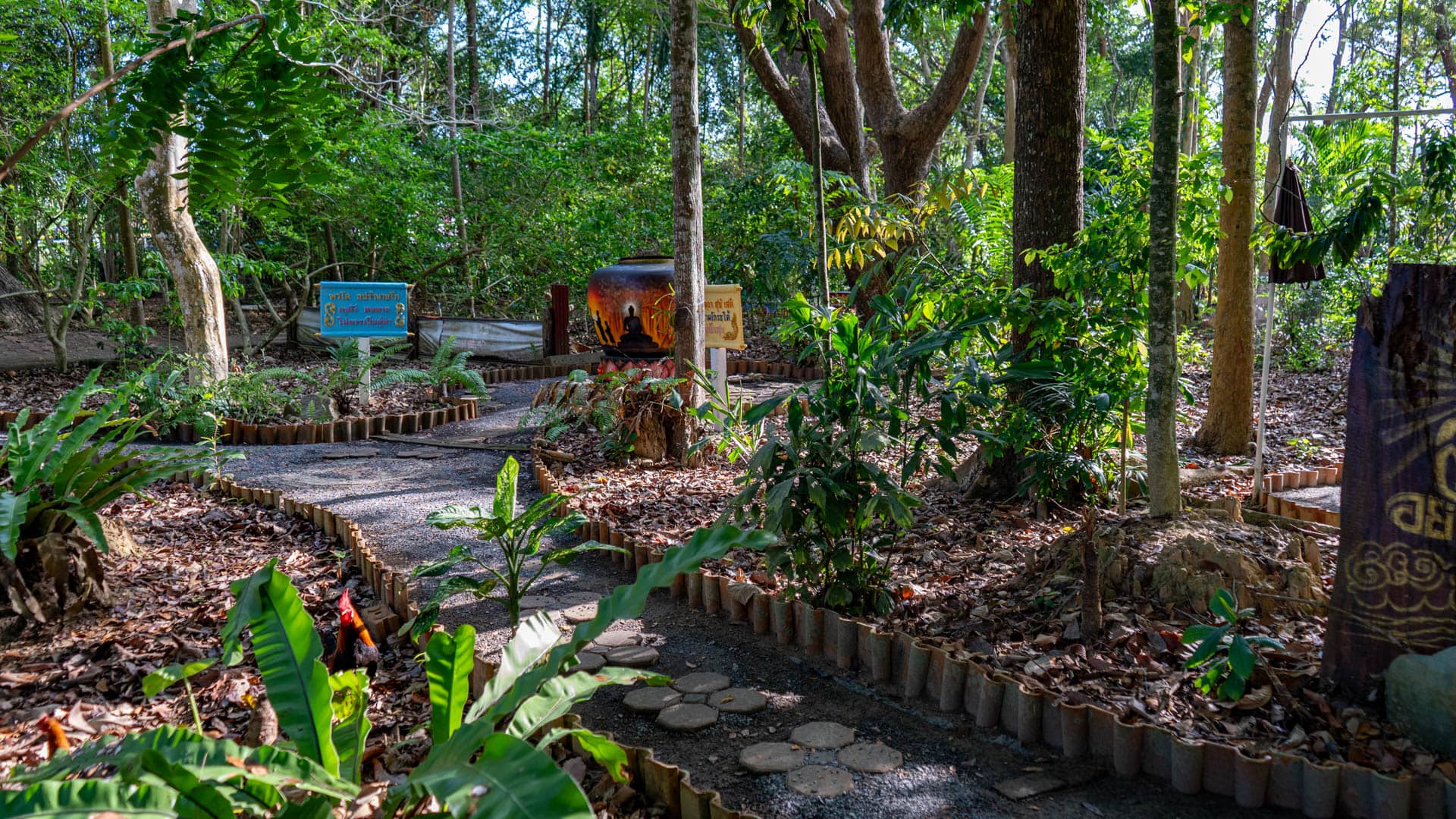 Curving path through wooded temple garden with signs and ceramic vessel