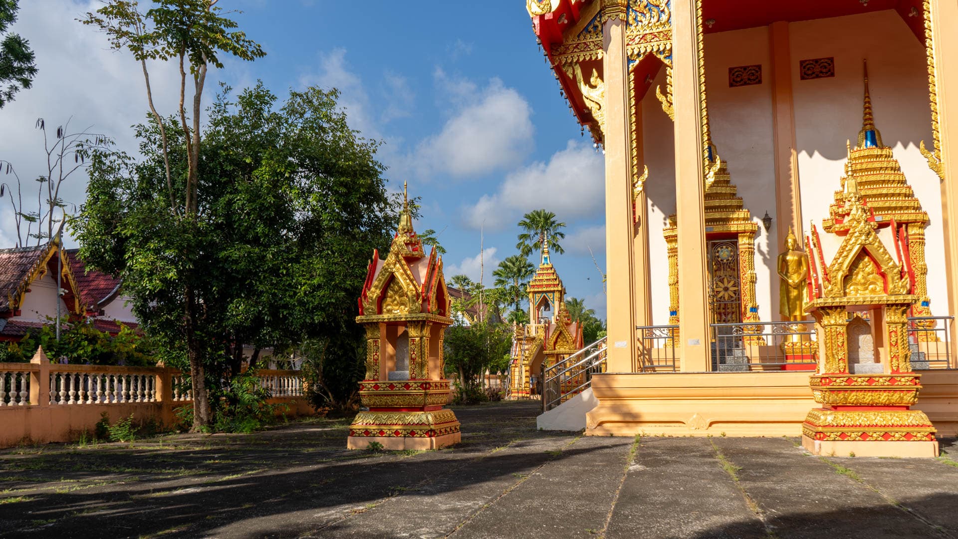 Shrine pavilions and standing Buddha beside main hall at Wat Phra Thong