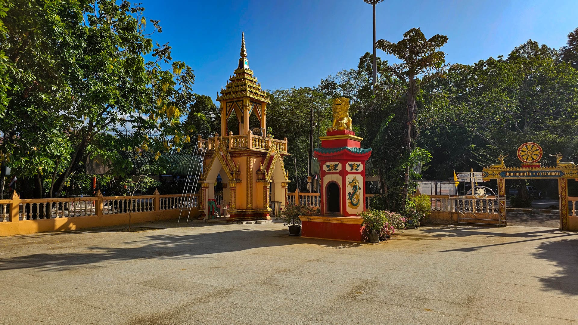 Bell tower, entrance forecourt, and red firecracker shrine at Wat Phra Thong gate