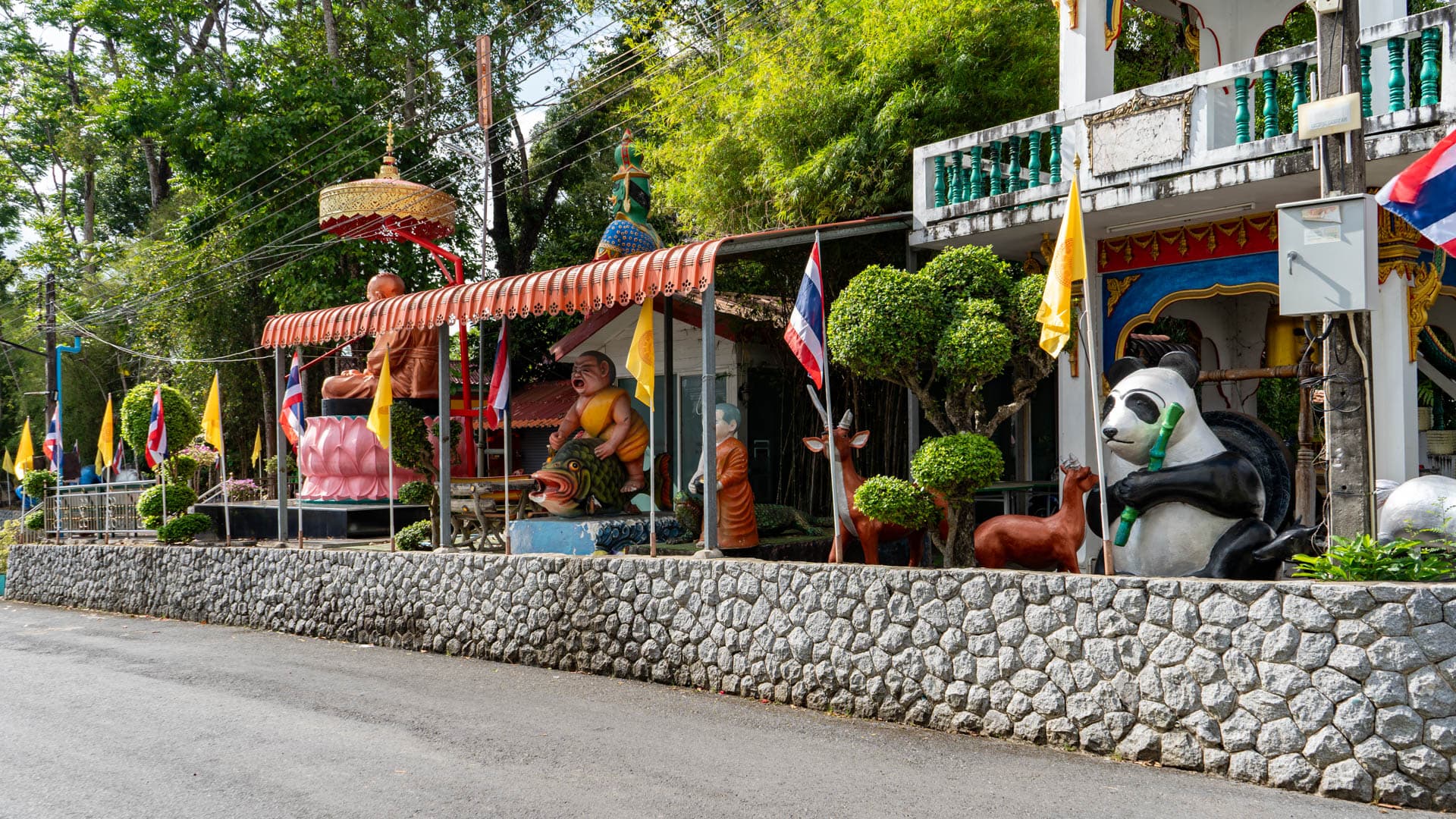 Decorative figures and flags along roadside edge of Wat Sri Sunthon